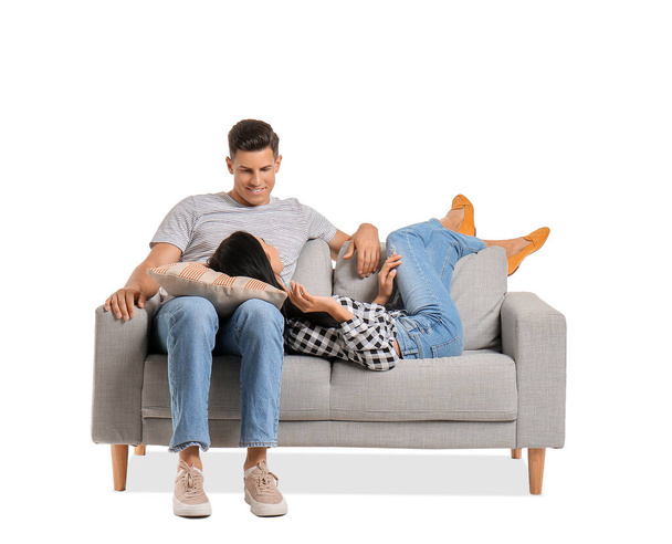 Νεαρό ζευγάρι χαλαρώνει στον καναπέ σε λευκό φόντο - Φωτογραφία, εικόνα