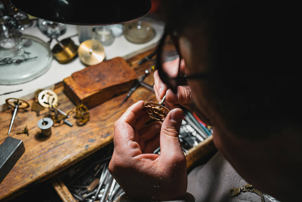 A high angle shot of a male working on repairing a watch - Fotografie, Obrázek