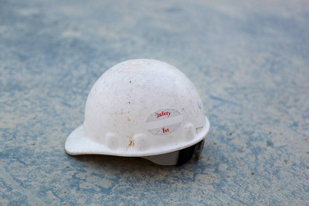 A shallow focus closeup shot of a white helmet with a "safety first" writing on the floor - Foto, Imagen