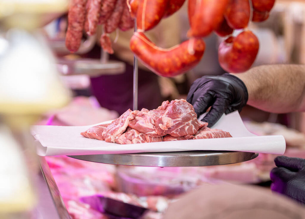 A closeup shot of a butcher's hands slicing up raw meat - Foto, afbeelding