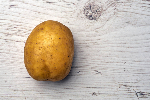 Top view of fresh raw potato on light wooden background                     - 写真・画像