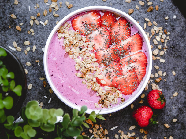 A top view of a healthy breakfast bowl with pink yogurt, oats, and strawberries - Foto, imagen