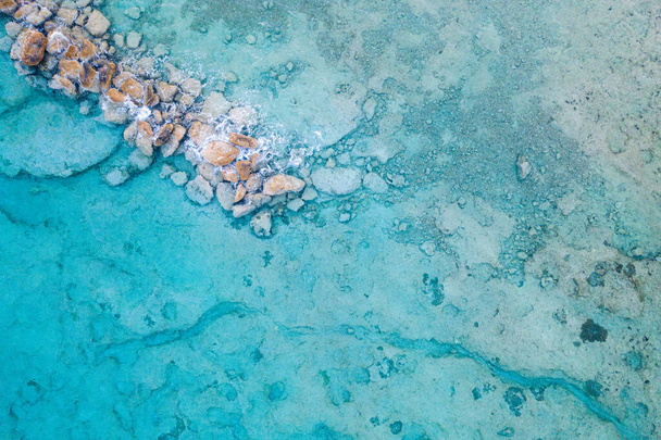 An aerial view of clear blue sea with rocks - Fotoğraf, Görsel