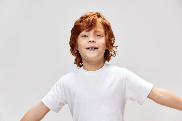 Portrét rusovlasého chlapce zábava hodí ruce bílé tričko  - Fotografie, Obrázek