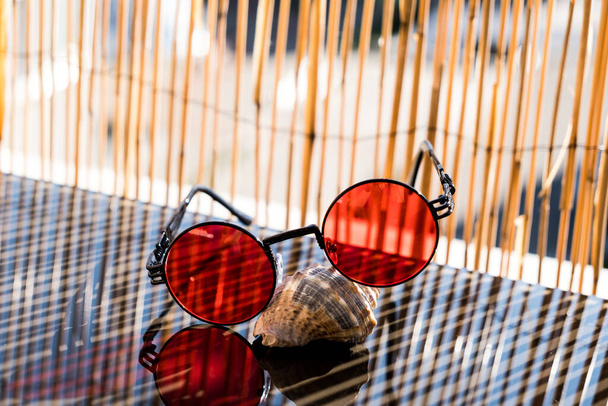 Стімпанк Сонцезахисні окуляри з червоною лінзою, розміщені на зйомці оболонки влітку в дуже сонячний день
  - Фото, зображення