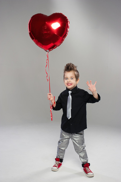Menino pequeno feliz com balão de coração vermelho em um fundo leve
 - Foto, Imagem