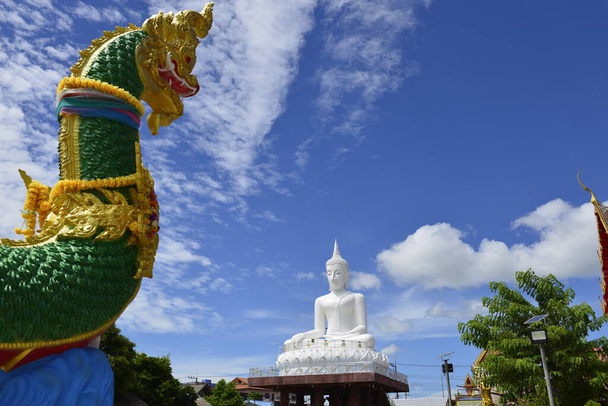 Ένα άγαλμα του Λευκού Βούδα με Naga Γλυπτική πρώτο πλάνο και μπλε φόντο του ουρανού στο Wat HaiSok, επαρχία NongKhai Ταϊλάνδη. - Φωτογραφία, εικόνα