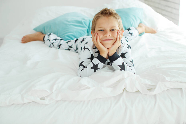 Kind op bed in pyjama. - Foto, afbeelding