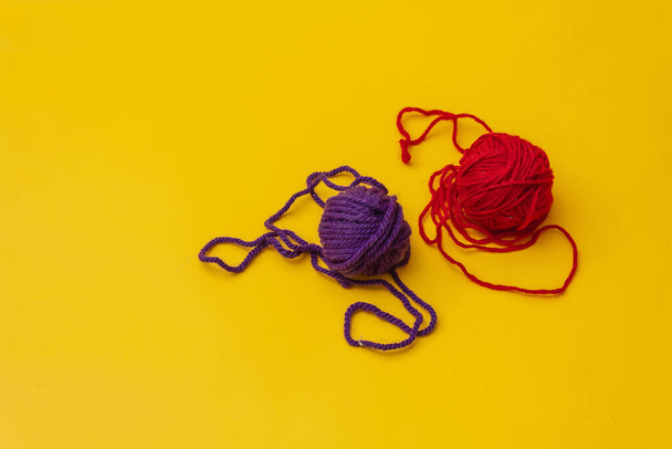 a tangles of red and blue woolen threads lies unraveled on a yellow background. the view from the top - Fotoğraf, Görsel