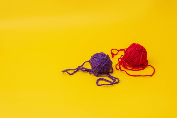 a tangles of red and blue woolen threads lies unraveled on a yellow background. the view from the top - Фото, изображение