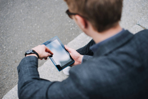Close up photo of man in suit using tablet outdoor in city - Foto, afbeelding