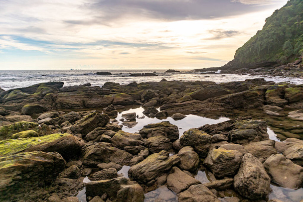 Beach rocks with sunset and calm cloudy sky. - Fotoğraf, Görsel