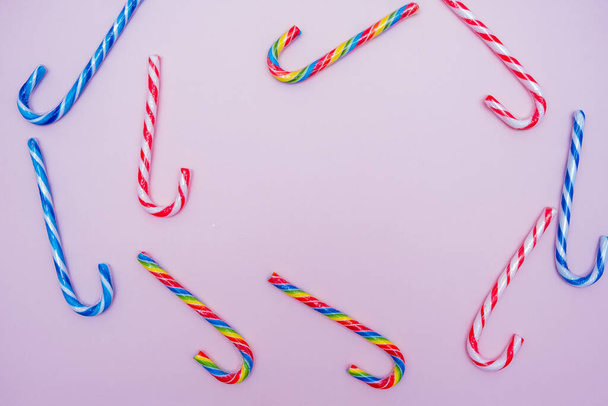 lot of multi-colored candy canes on a pink background, copy space - Foto, afbeelding