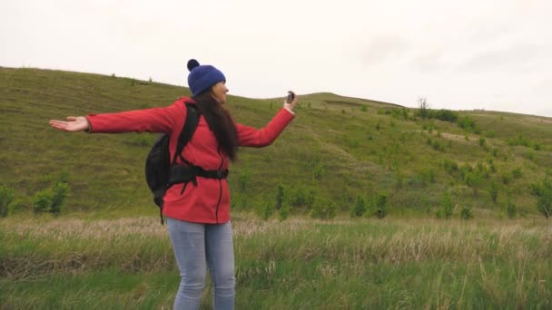 Gezonde vrolijke vrouw reist en fotografeert de natuur telefonisch. gratis jong meisje toeristische blogger records selfie video 's aan de voet van de bergen met behulp van een smartphone met een prachtig landschap op de achtergrond. - Video