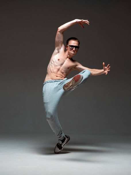 Crazy young guy breakdancer in sunglasses dancing hip-hop without shirt in studio. Dance school poster - Foto, Imagen