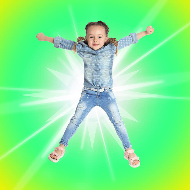 Cute little girl jumping on colorful background. School holidays - 写真・画像