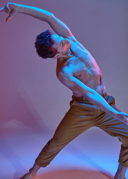 Cool young guy dancing expressive dance without shirt in neon light. Colorful dance school poster. Cropped photography - Photo, Image