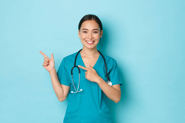 Ковид-19, социальная дистанцированность и пандемическое понятие коронавируса. Профессиональный врач, медсестра или врач в форме информируют пациентов, указывая пальцами в левом верхнем углу, показывая баннер клиники - Фото, изображение