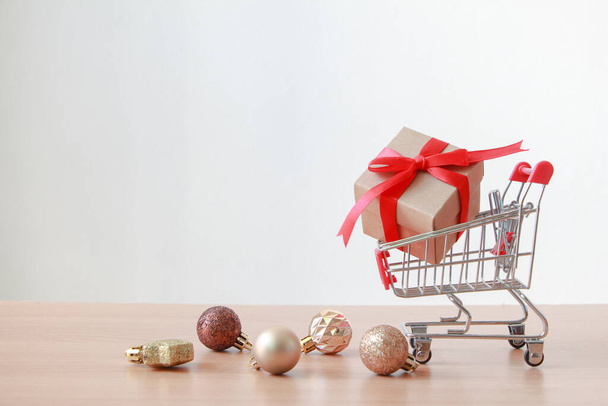 Caja de regalo en miniatura carrito de compras sobre fondo blanco. Navidad y feliz año nuevo concepto. - Foto, imagen