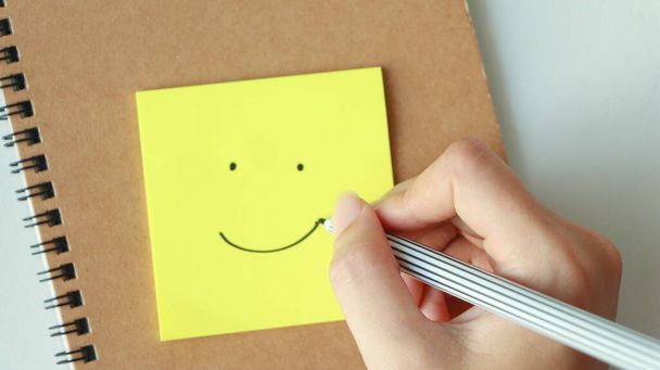 Tekenen glimlach gezicht op plakkerig papier nota. - Foto, afbeelding