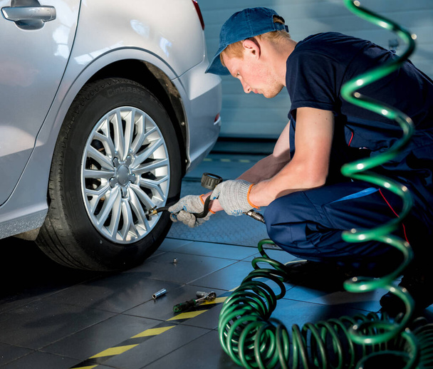 Professional car mechanic working with in auto repair service. Repair of wheels - Фото, зображення