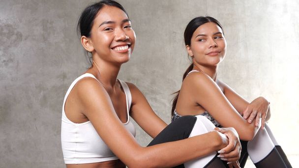 İki güzel Asyalı kadın spor salonunda mola veriyor. Mutlu bayan arkadaşlar boş zamanlarını spor merkezinde geçiriyorlar. - Fotoğraf, Görsel
