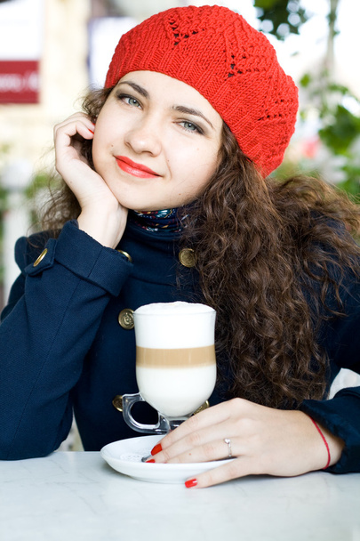 Young beautiful brunette with a delicious latte in a street cafe - Φωτογραφία, εικόνα