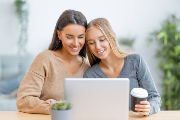 Two happy young women using laptop. Friends spending time together. - Φωτογραφία, εικόνα