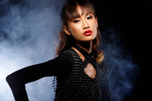 Portrait of 20s Asian Woman tanned skin brown blonde hair style Cosmetic Make up, black dress red lips. Girl poses over dark Background isolated - Φωτογραφία, εικόνα