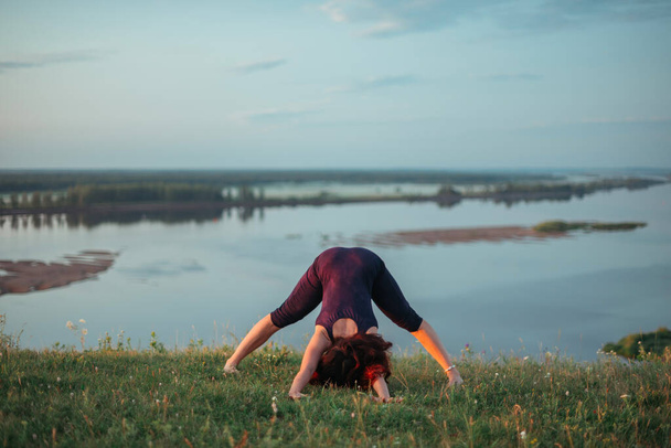 Yoga-Praxis und Meditation in der Natur bei Sonnenaufgang. Frau übt in der Nähe des großen Flusses Kama. - Foto, Bild