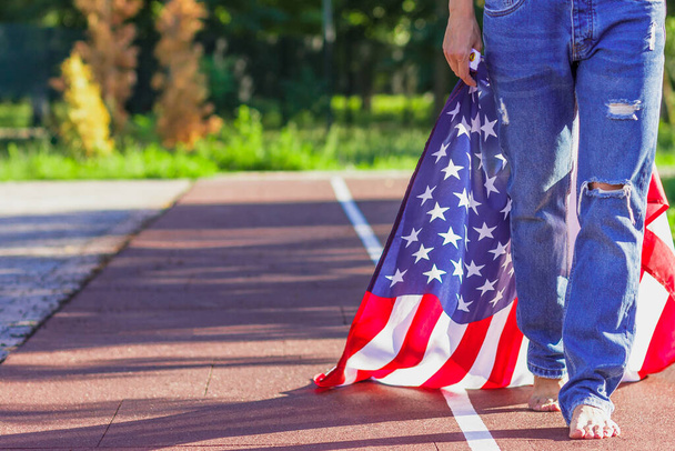 Woman with a flag of United States of America in the hands, outdoors, soft focus background - Foto, imagen