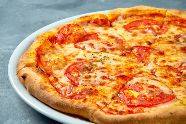 Classic italian pizza margarita with tomatoes and cheese in a white plate on a concrete background - Foto, Imagem