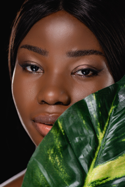 african american woman with green exotic leaf isolated on black - Фото, изображение
