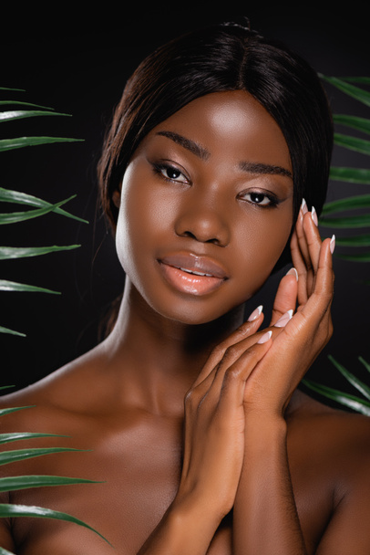 афро-американська гола жінка біля зеленого пальмового листя ізольована на чорному
 - Фото, зображення
