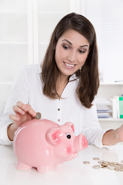 Smiling attractive caucasian business woman with piggy bank at o - Фото, зображення