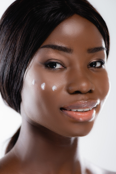 Αφροαμερικανή γυναίκα με καλλυντική κρέμα στο πρόσωπο που απομονώνεται σε λευκό - Φωτογραφία, εικόνα