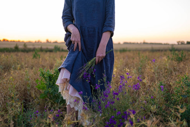 Young redhead woman with  freckles in vintage handmade dress walk in fields with flowers  - Foto, imagen