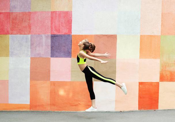 Fitness sport young girl in sportswear doing yoga fitness exercise on a wall background. Sporty gymnast child preteen training outdoor. Healthy lifestyle and bodycare concept - Foto, Bild