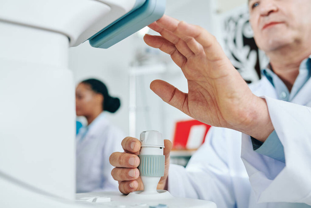 Image en gros plan d'un ophtalmologiste utilisant un équipement moderne pour vérifier la vue du patient - Photo, image