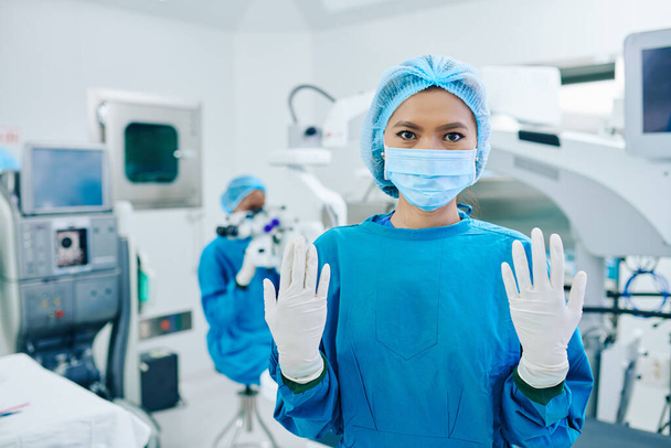 白い滅菌手袋で手を示すスクラブや医療用マスクで若いアジアの女性外科医 - 写真・画像
