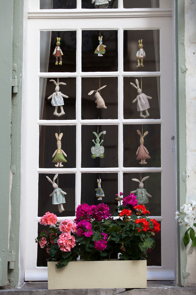Белое окно с цветочным горшком и смешными висячими куклами
 - Фото, изображение
