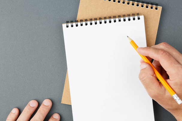 Σημειωματάριο σαφή σελίδα και αρσενικά χέρια με μολύβι. - Φωτογραφία, εικόνα