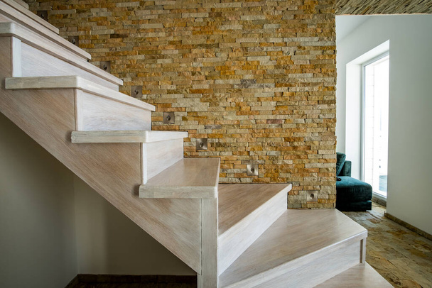 Stilvolle zeitgenössische Holztreppe im Inneren des Loft-Hauses. Moderner Flur mit dekorativen Kalksteinmauern und Treppen aus weißer Eiche. - Foto, Bild
