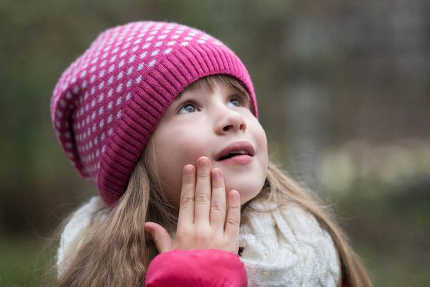 Pretty child girl in warm knitted winter clothes outdoors. - Photo, Image