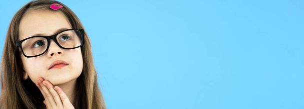 close-up portret van een kind school meisje dragen uiterlijk bril geïsoleerd op blauwe achtergrond. - Foto, afbeelding