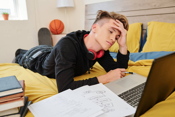 College szoftver mérnök hallgató figyeli webinar a nehéz téma online, amikor fekszik az ágyban kollégiumban - Fotó, kép