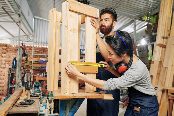 Equipe de carpinteiros medindo suporte de madeira que fizeram na oficina - Foto, Imagem