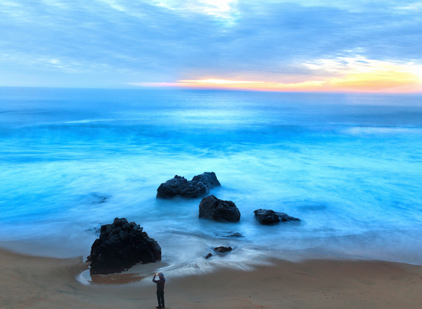людина фотографування гуркіт хвиль на захід сонця з мобільного телефону - Fotó, kép