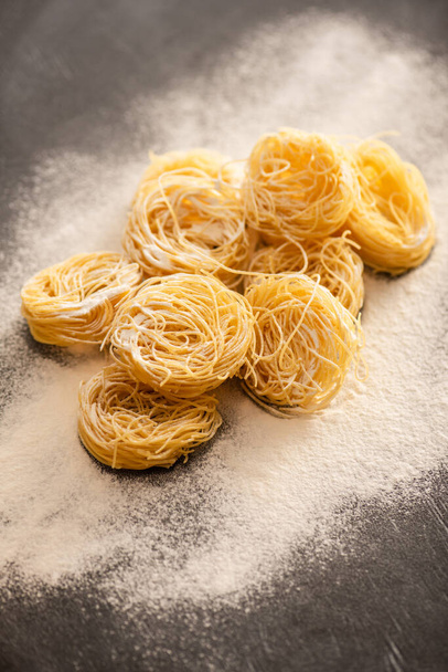 raw Italian Capellini with flour on black background - Photo, Image