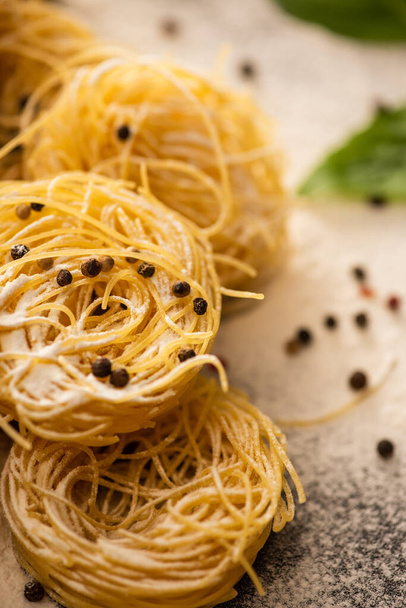 close up view of raw Italian Capellini with flour and black pepper - Foto, Bild